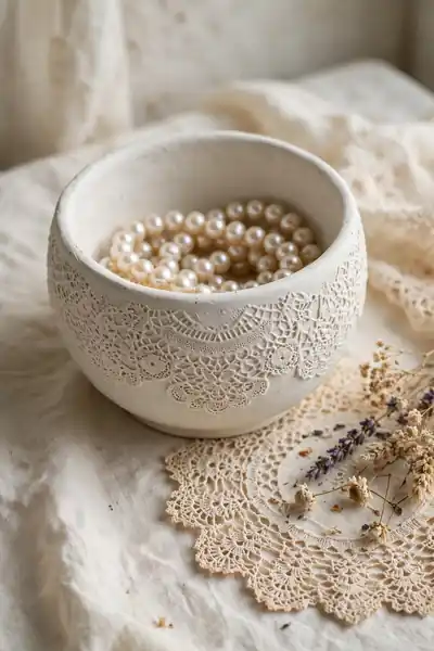 Clay bowl with lace doily imprint holding pearl jewelry