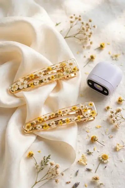 Two gold hair clips with pressed white and yellow flowers in clear resin