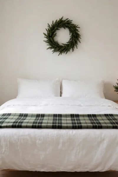 Small bedroom with one mini tree one wreath and clear floor